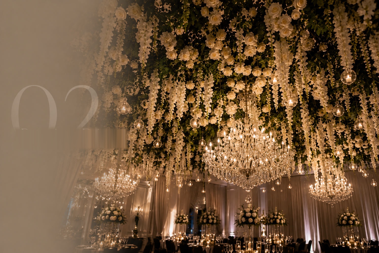 Suspended floral ceiling installation cascading above an elegant reception
